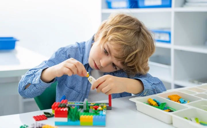 chłopczyk około 6 lat bawiąący się zestawem LEGO